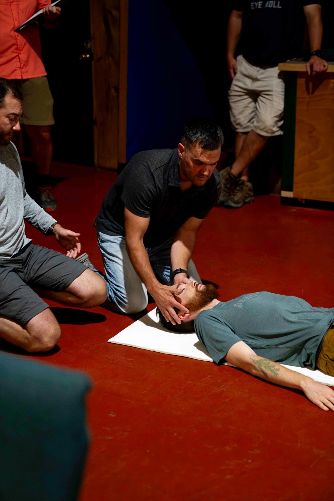Instructor practicing CPR on a training manikin on the floor