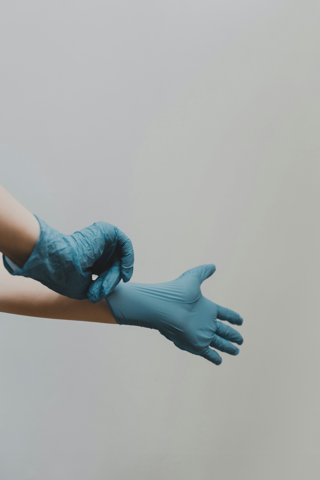 Person putting on blue medical exam gloves